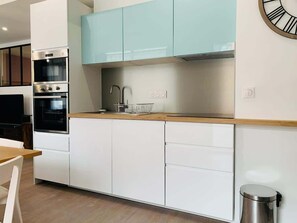 A modern kitchen with white cabinets, a stainless steel range, and a light blue upper cabinet. - Beautiful 3-bedroom apartment / Porte de Versailles (Paris)