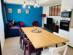 Eine moderne Küche mit einem Holztisch, roten Stühlen und einer blauen Wand mit Kunstwerken.