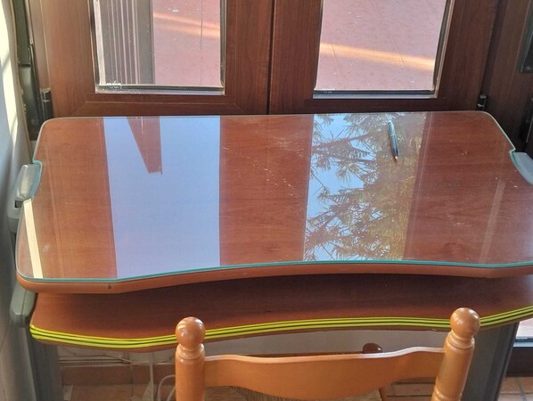 Une chaise en bois et une table en verre, devant une fenêtre.