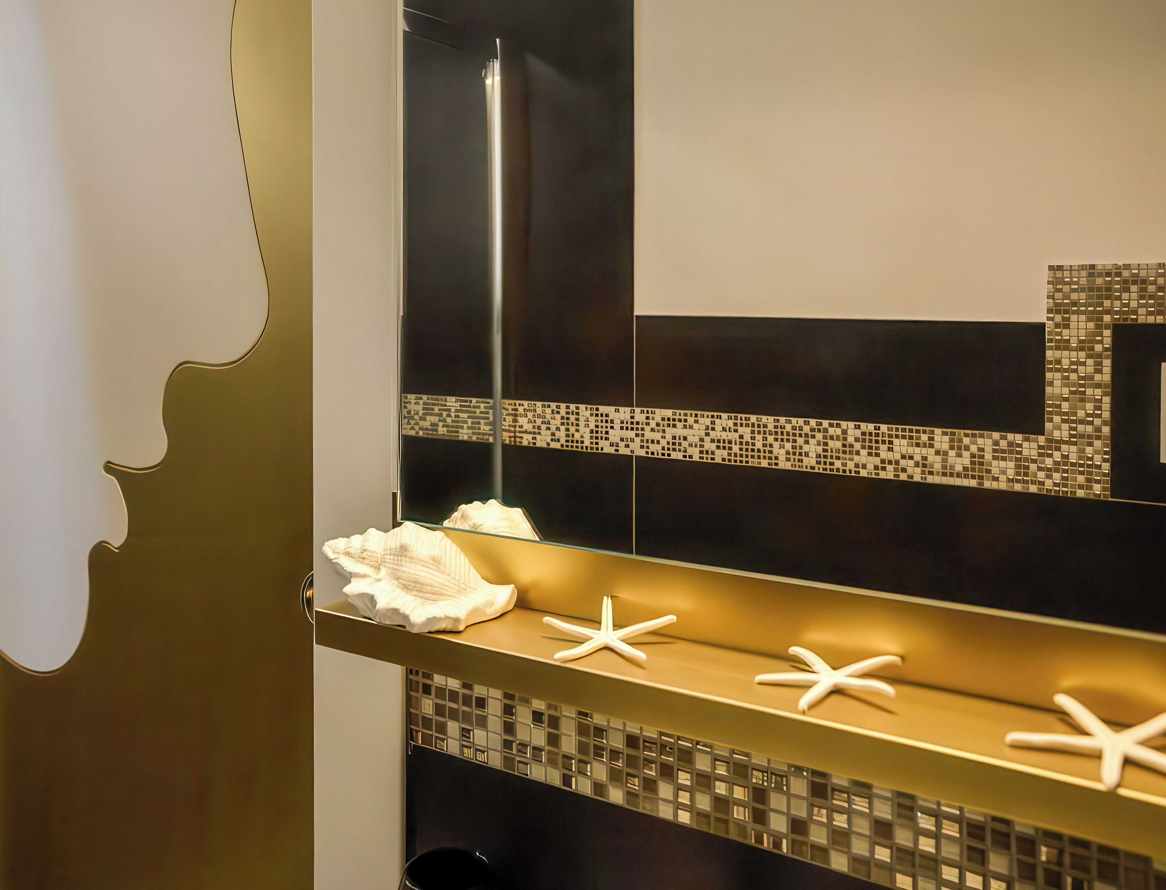 Un baño con un espejo grande, decoraciones de estrella de mar y un salpicadero de azulejos.