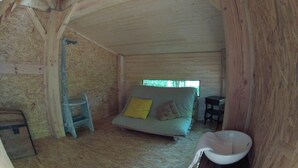 A room with a bed, a chair, a small table, and a toilet.