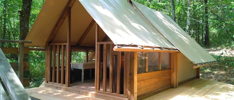 A wooden cabin with a pitched roof, a deck, and a window.