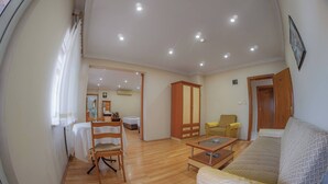 Un salon spacieux comprenant un canapé, une table à manger avec des chaises, un meuble en bois et une petite table avec un plateau en verre.