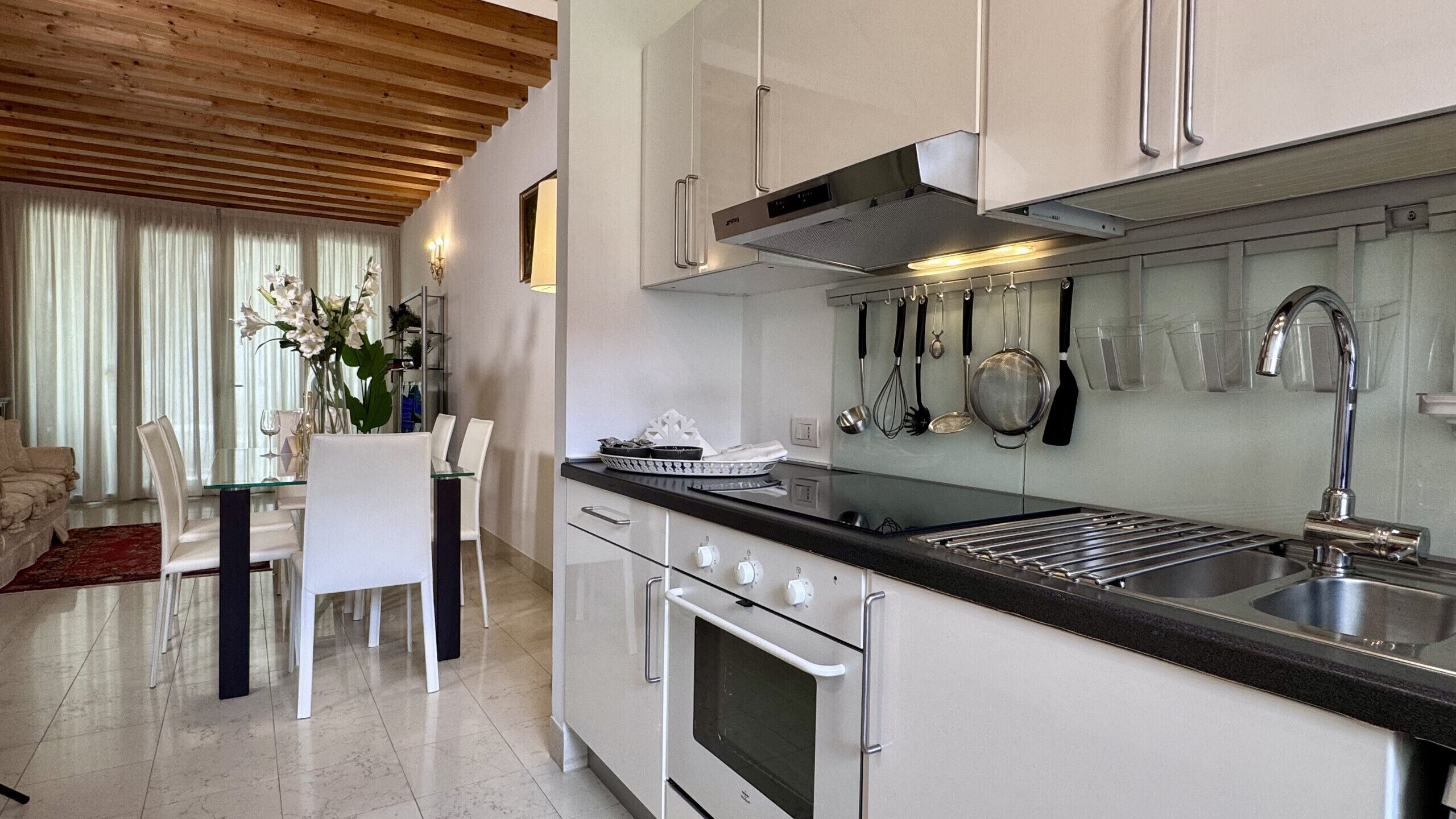 A modern kitchen with white cabinets, stainless steel appliances, and a dining area with a glass table and chairs.