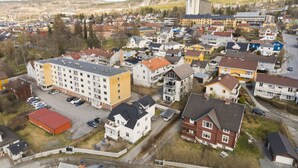 Ein Wohngebiet mit einer Mischung aus Reihen- und Mehrfamilienhäusern, einem Parkplatz und einem großen Gebäude mit Flachdach.