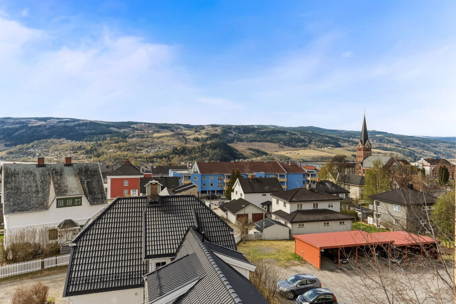A residential area with houses, a church, and a hill in the background.