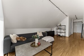 Ein stilvolles Loft mit hohem Schlafsofa, einem grauen Sofa, einem Couchtisch und einer schwarzen Regaleinrichtung.