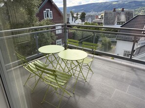 A balcony with a glass railing, two round tables, and four chairs. - Great location and view in Lillehammer (Lillehammer)