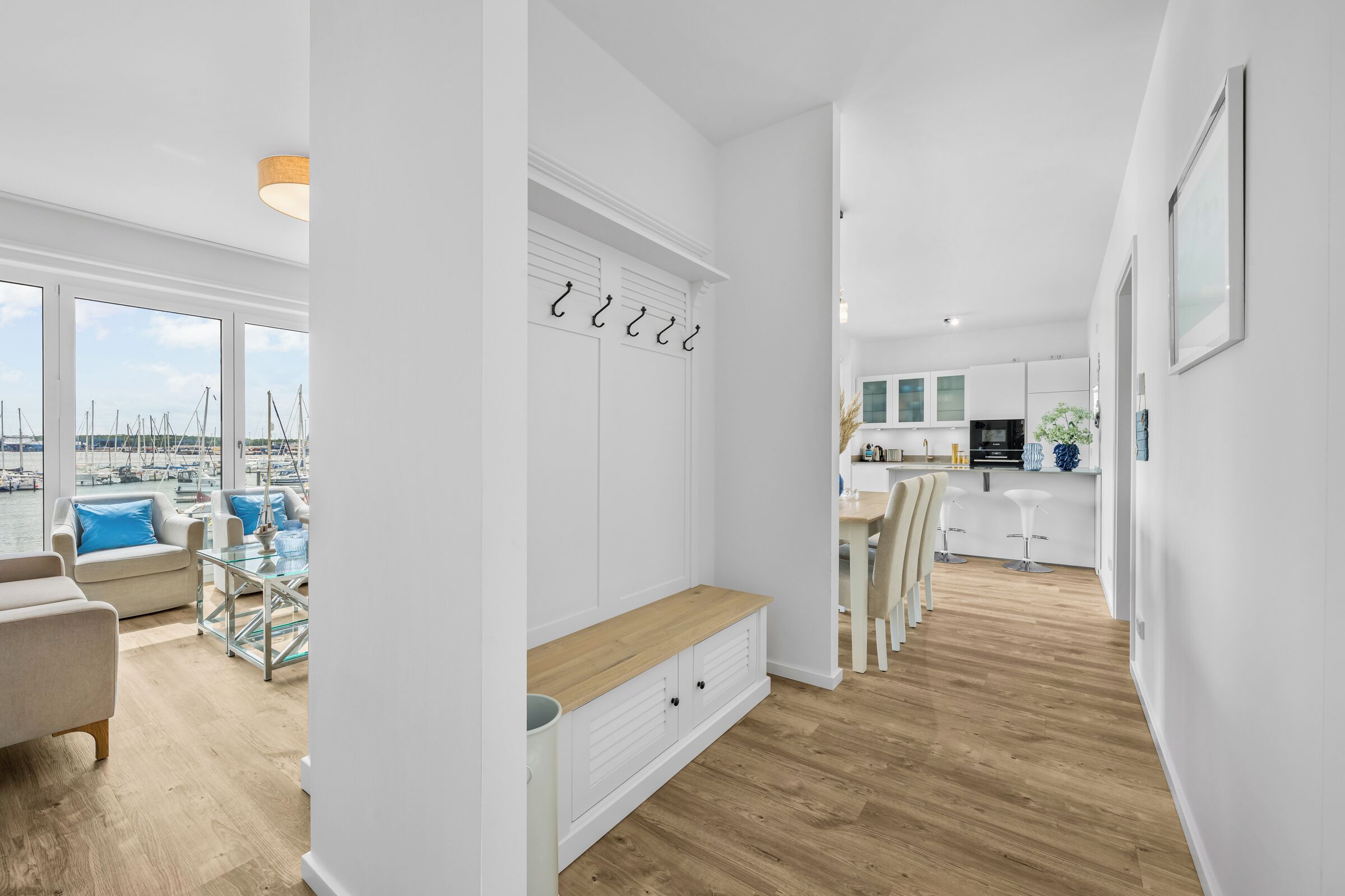 Een modern interieur met een zithoek, een keuken en uitzicht op een jachthaven.