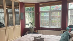 A bedroom with a bed, a radiator, a window, and a ceiling fan. - Garden Flat - Sleeps 6 (London)