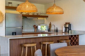 A modern kitchen with a central island, bar stools, and pendant lighting. - Ka'anal: 2BR Space w 2 Bikes & FREE Beach Shuttle (Tulum Municipality)