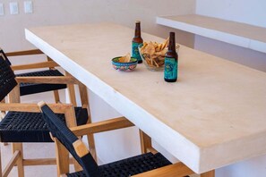 A dining table with chairs, bottles, and a bowl of chips. - Ka'anal: 2BR Space w 2 Bikes & FREE Beach Shuttle (Tulum Municipality)