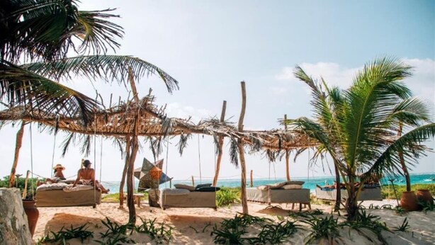 Eine Strandlandschaft mit strohgedeckten Gebäuden und Liegestühlen.