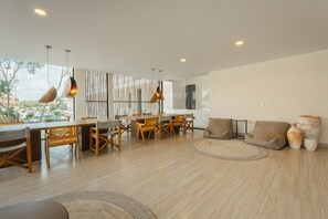 A modern living room with a dining area, featuring wooden furniture, large windows, and a view of the outside. - Best Location & Views of Jaguar Park (Tulum Municipality)