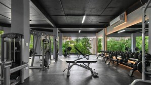 Ein Fitnessstudio mit verschiedenen Trainingsgeräten, darunter Laufbänder, Kraftgeräte und Kurzhanteln.