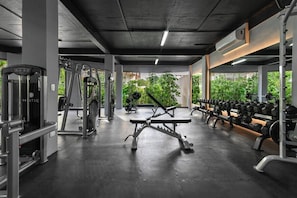 Academia com diversos equipamentos de ginástica, incluindo esteiras, aparelhos de musculação e halteres.