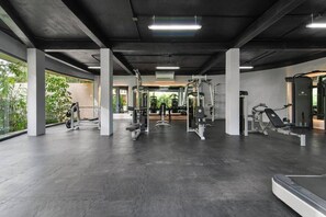 Une salle de sport équipée de divers appareils d’exercice, d’un banc et d’un support à poids.