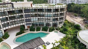 A multi-story building with a pool, surrounded by greenery and a landscaped area. - Ki'Che': An Intimate 1-Bedroom Loft (Tulum)