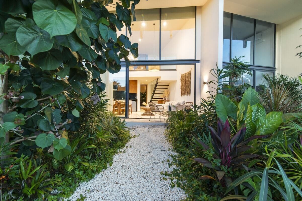 A modern building with a gravel pathway leading to a staircase and a seating area.