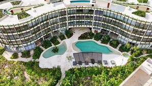 Ein mehrstöckiges Hotel mit geschwungener Außenfassade, zahlreichen Balkonen und einem Innenhof mit Pool.