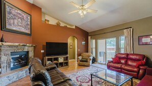 A living room with a fireplace, leather sofas, a flat-screen TV, and a ceiling fan. - Single level 3 bedroom house in Pagosa Springs with a fenced backyard (Pagosa Springs)