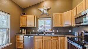 A kitchen with wooden cabinets, a dishwasher, a microwave, and a star decoration on the wall. - Single level 3 bedroom house in Pagosa Springs with a fenced backyard (Pagosa Springs)