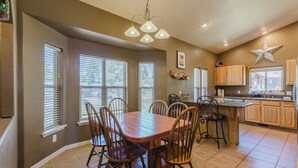 A dining area with a wooden table and chairs, a chandelier, and a kitchen with wooden cabinets and a star decoration. - Single level 3 bedroom house in Pagosa Springs with a fenced backyard (Pagosa Springs)