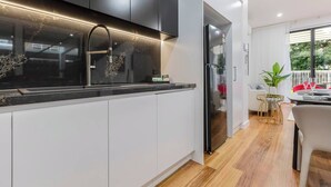 Uma cozinha moderna com bancada preta, armários brancos e uma geladeira de aço inoxidável.