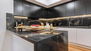 Uma cozinha moderna com armários escuros, bancada de mármore e uma ilha central com tampo de madeira.