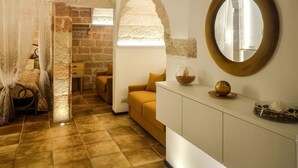 A room with a bed, a sofa, a dining area, and a large mirror. - Gold White Exclusive House (Polignano a Mare)
