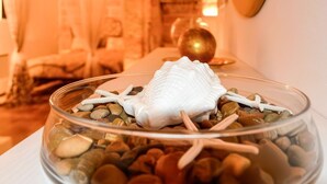 A clear glass bowl with a white object and starfish on a bed of pebbles. - Gold White Exclusive House (Polignano a Mare)