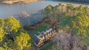A large house with a spacious lawn and a lake in the background. - The Sanctuary at Morris Creek | 4BR Luxury Stay (Charles City)