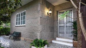A stone building with a bench, a light fixture, and a door with a gate. - Home, beach, and garden. (O Grove)