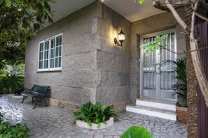 Ein Steinhaus mit einer Bank, einer Lampe und einer Tür mit einem Tor.