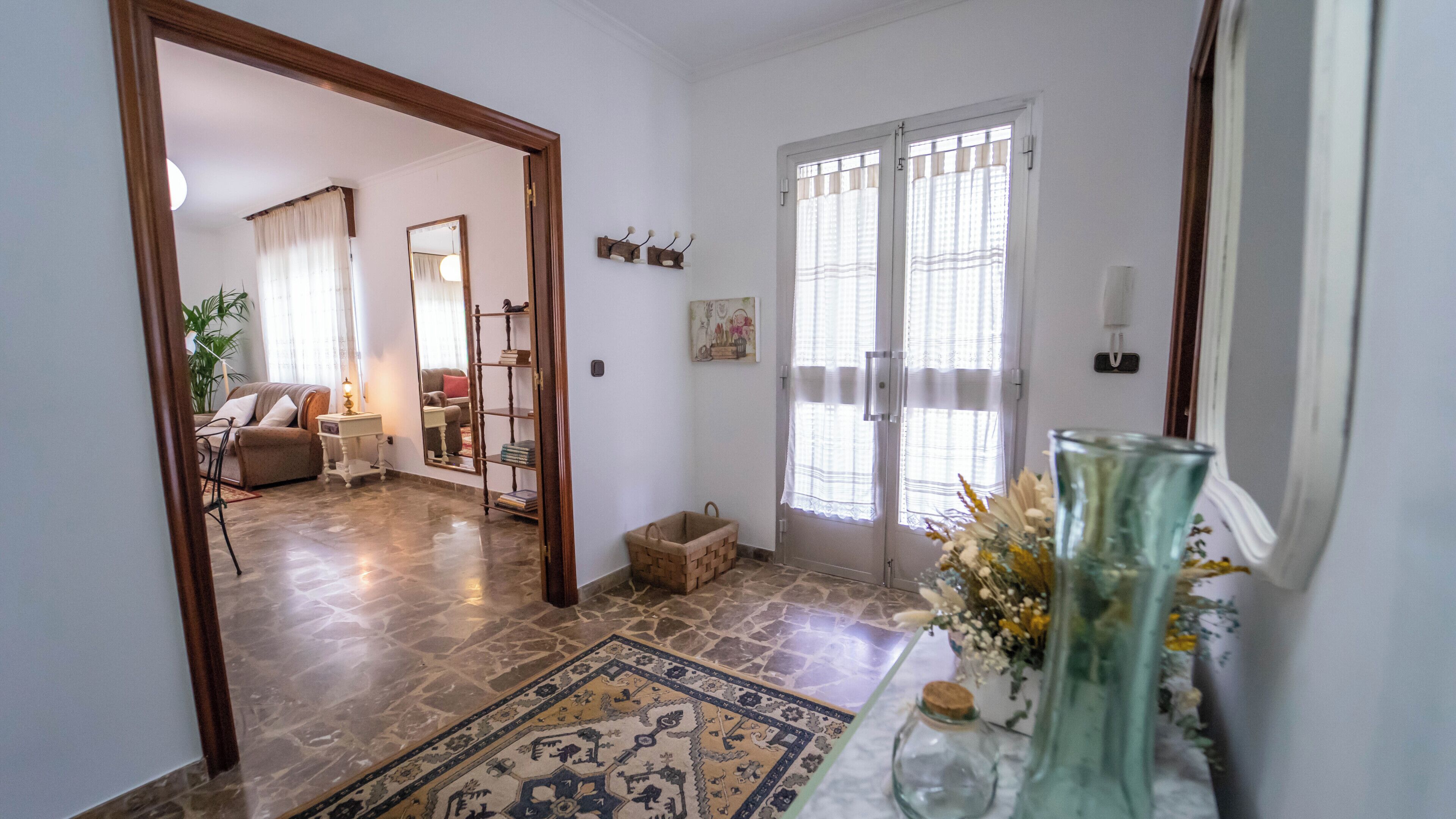A spacious living area with a sofa, a coffee table with a vase, and a rug.