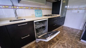 A kitchen with a dishwasher, stove, sink, and cabinets. - Home, beach, and garden. (O Grove)