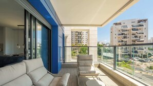 Un balcone con un divano, una sedia e un tavolo, con vista sulla città.