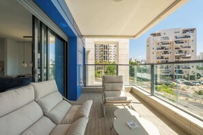 Ein Balkon mit Sofa, Stuhl und Tisch mit Blick auf die Stadt.