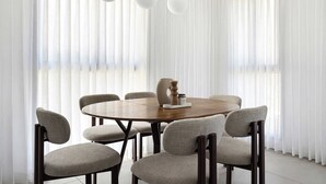 Un'area pranzo con un tavolo rotondo, sei sedie e tre lampadari a sospensione.