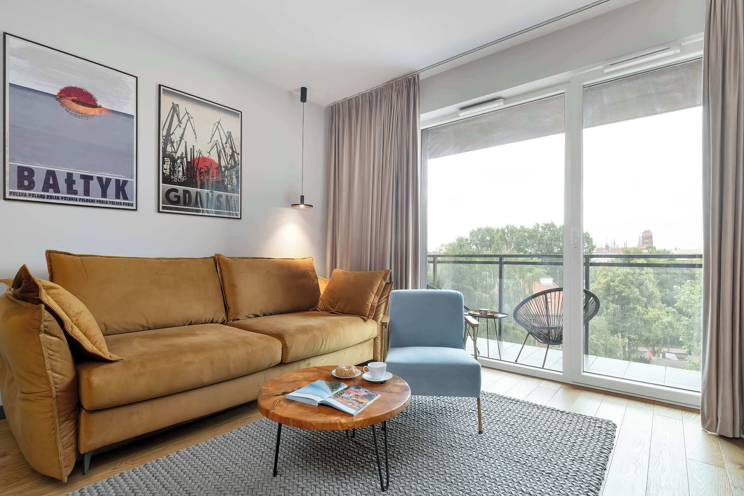 A modern living room with a sofa, armchair, coffee table, and large windows.