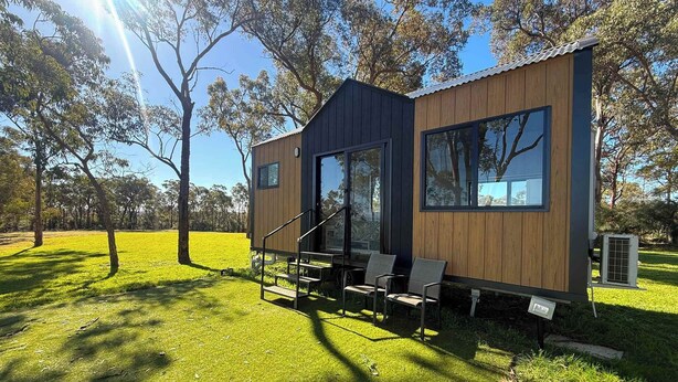 Un edificio moderno de madera de dos pisos con un balcón y zona de estar al aire libre.