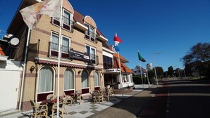 Un hôtel doté d’une terrasse, d’un balcon et de drapeaux.