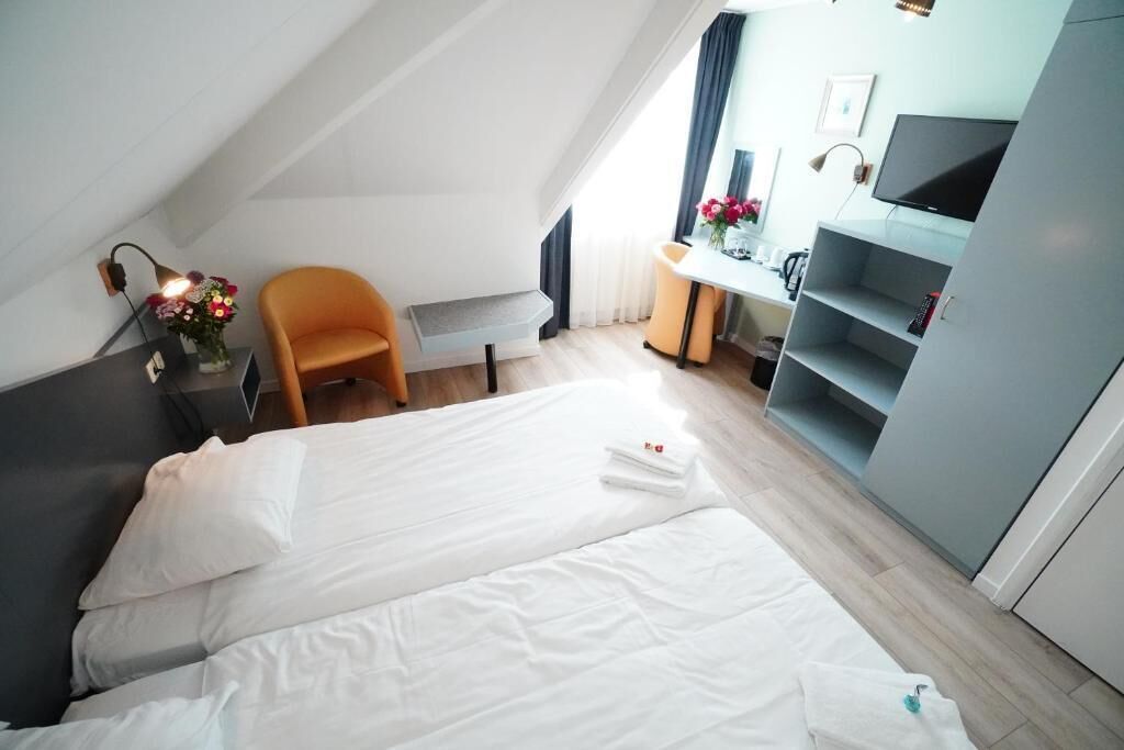 A hotel room with a bed, a desk, a chair, and a TV.