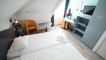 A hotel room with a bed, a desk, a chair, and a TV.