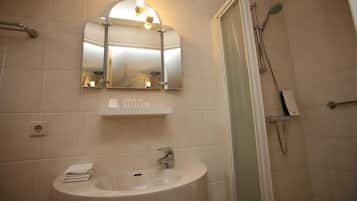 A bathroom with a sink, mirror, and shower.