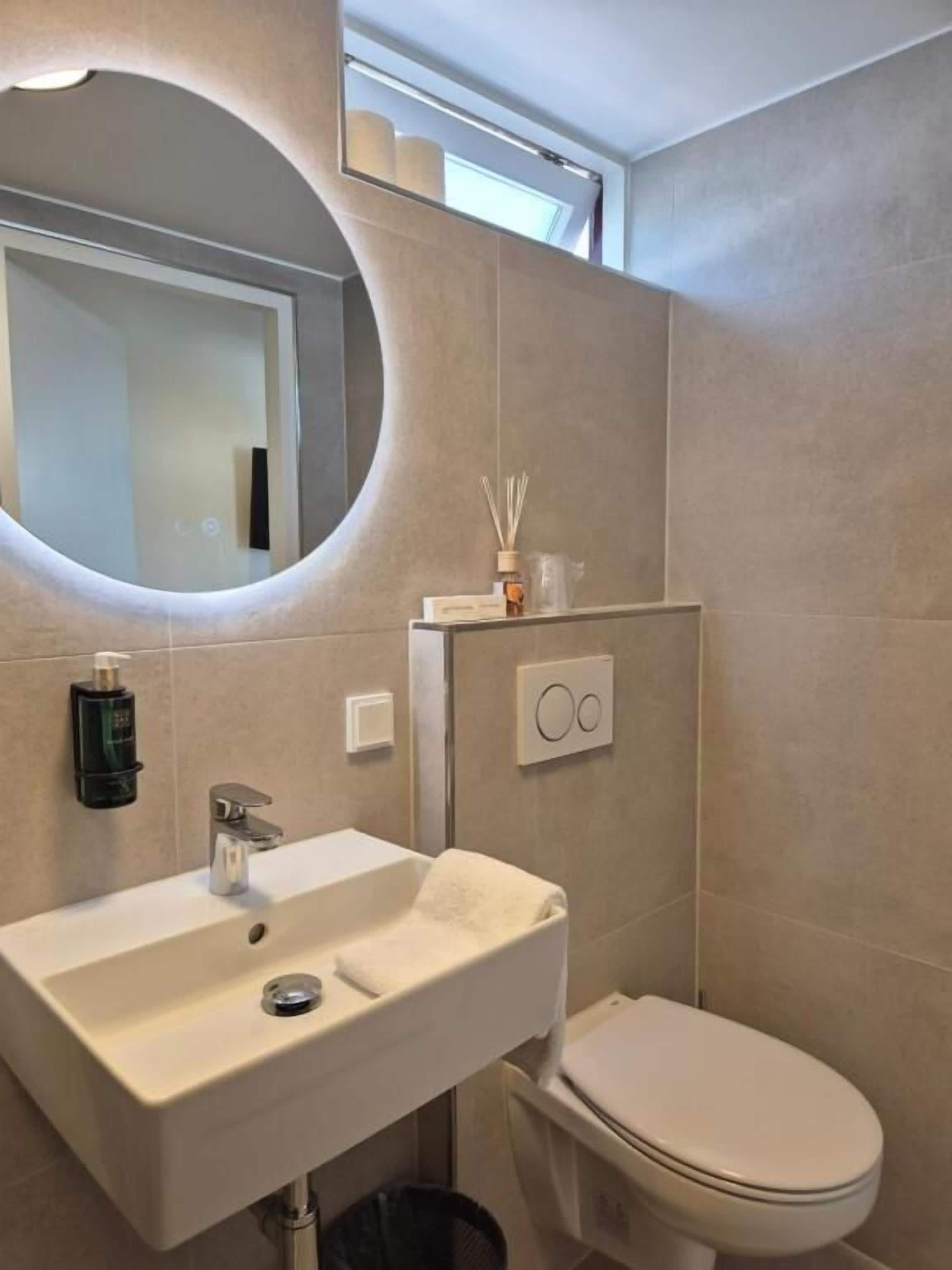 Une salle de bain avec un lavabo, des toilettes et un miroir.