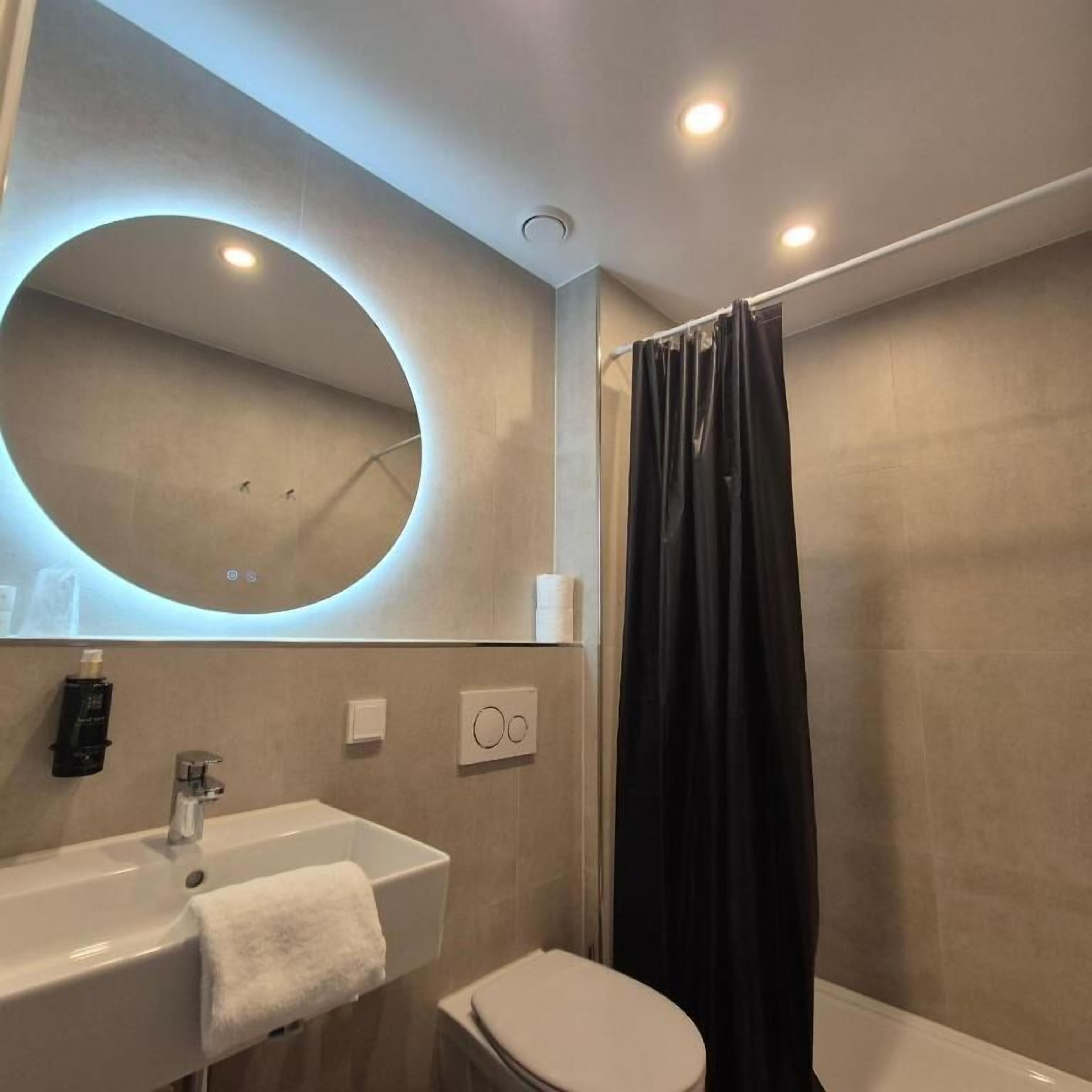 A bathroom with a sink, toilet, and shower curtain.