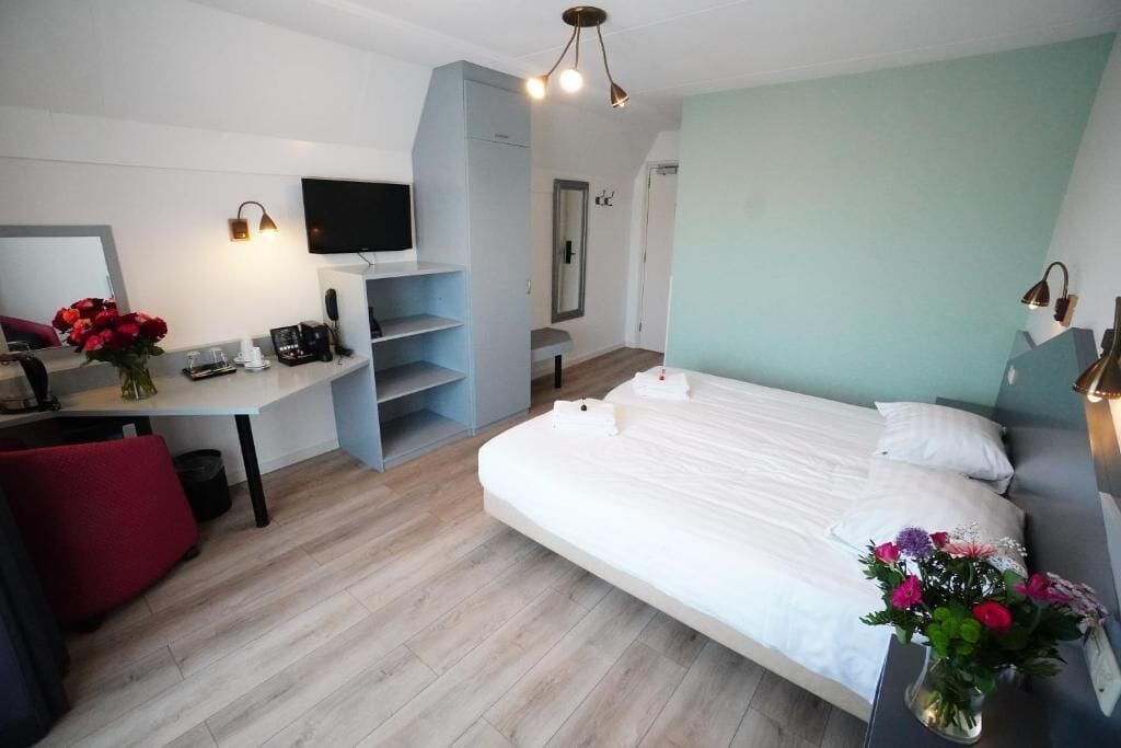 Una habitación de hotel moderna con cama, escritorio, televisión y espejo.
