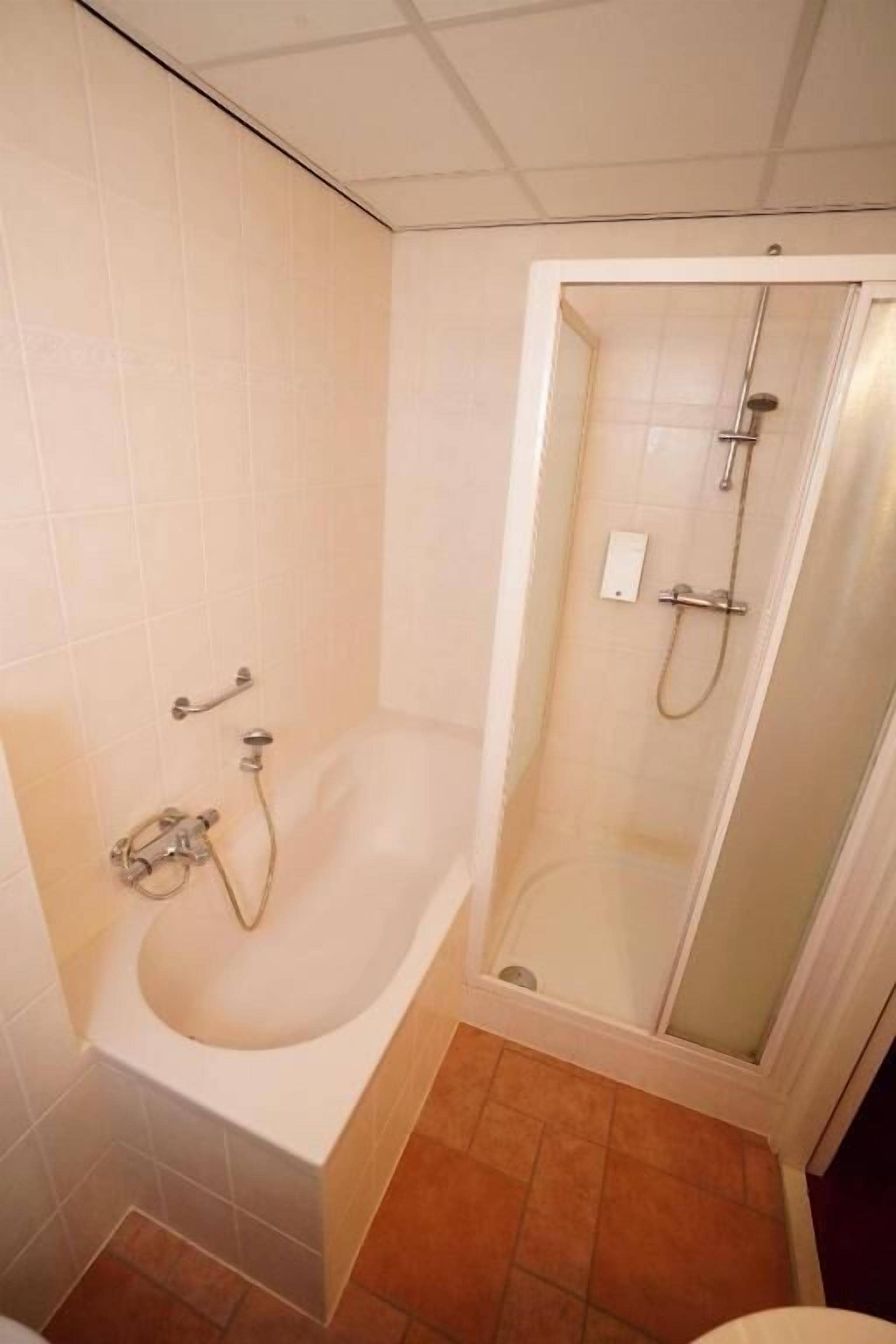 A bathroom with a bathtub, shower, and toilet.