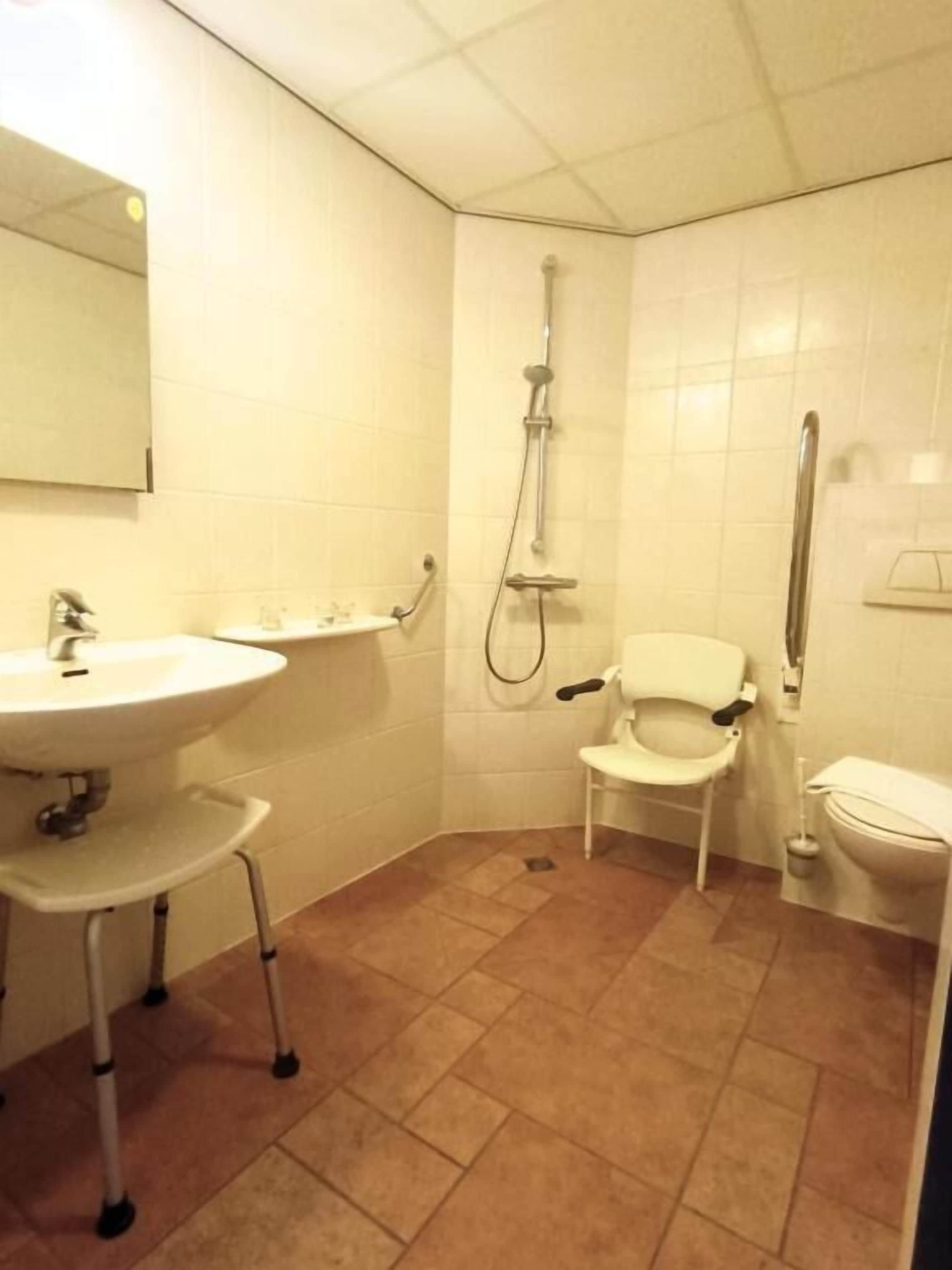 Un baño con lavamanos, espejo, inodoro y ducha.